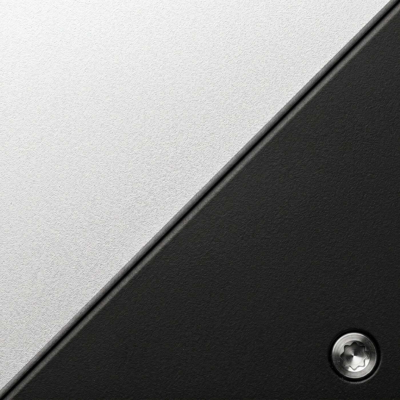 Macro detail of the bead-blasted anodized-silver chassis meeting the matte-black handset; one captive screw visible.